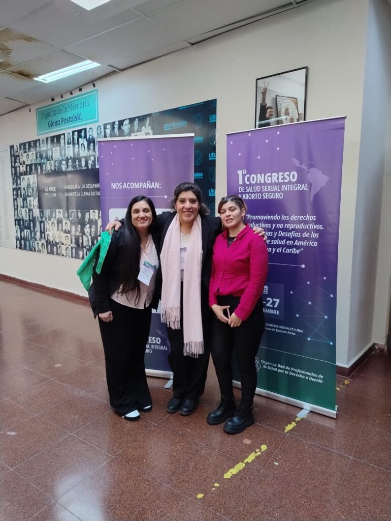 Estefanía Rearte Peredo, Griselda Pavón y Karen Burgos, las tres enfermeras, posan detrás de un cartel de la red de profesionales de la salud por el derecho a decidir. 